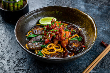 chicken in teriyaki sauce with fried noodles on dark stone table