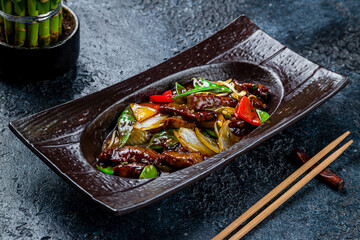 roast beef in oyster sauce with vegetables on dark stone table