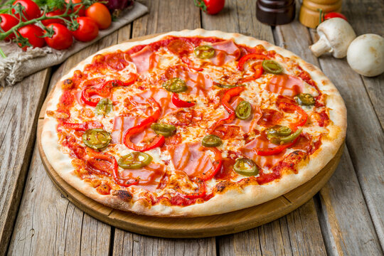 Mexican pizza with meat and jalapeno, cheese and tomato sauce on wooden table close up