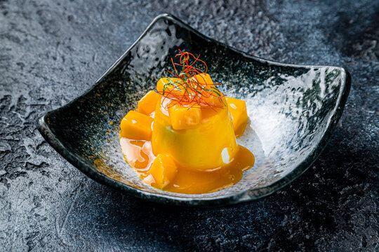 panna cotta with mango sauce on dark stone table