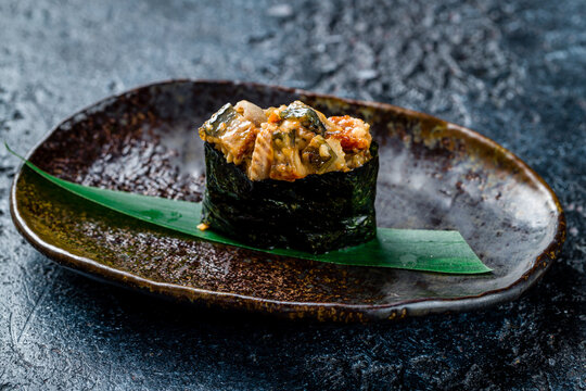 Sushi gunkan with spicy eel on dark stone table
