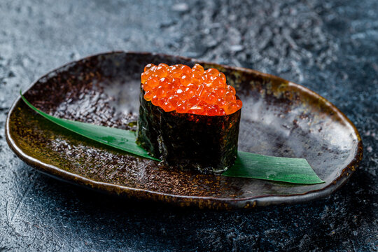 sushi Gunkan with red caviar on dark stone table