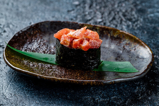 Sushi gunkan with spicy tuna on dark stone table