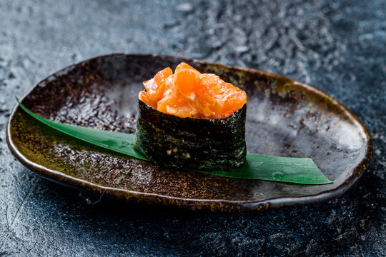 Sushi gunkan with spicy salmon on dark stone table