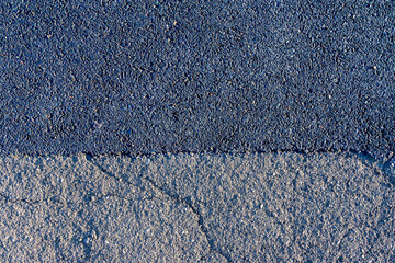 Old cracked from use gray asphalt merges with new black asphalt