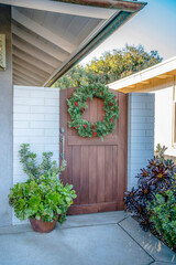 Fototapeta na wymiar La Jolla, California- Single wooden gate with wreath and plants at the side of the house