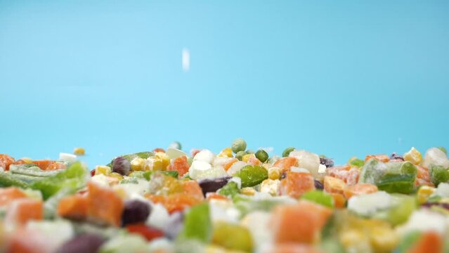falling frozen vegetables assorted, flying food on blue background High quality FullHD footage