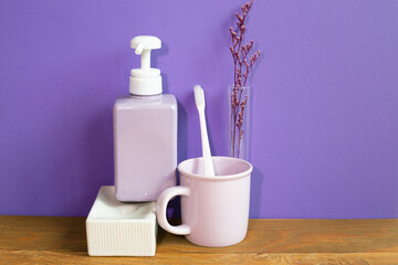 Bathroom accessories hygiene objects on wooden table. purple wall background