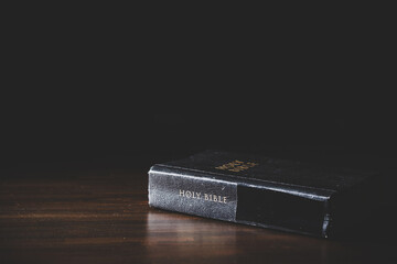 Holy bible book with paper for education on black wooden background. Christian catholic with protestant worship and pray in church. Concept of learning about faith god and religion, jesus spiritual.