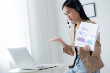 Young asian business woman using laptop computer for video conference online, businesswoman working with video call for meeting and showing graph report for finance, communication concept.