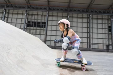 Foto auf Acrylglas asian child skater or kid girl playing skateboard or riding surf skate up to wave ramp or wave bank to fun bottom turn and sweating in skate park by sports exercise to wearing helmet for body safety © kornnphoto