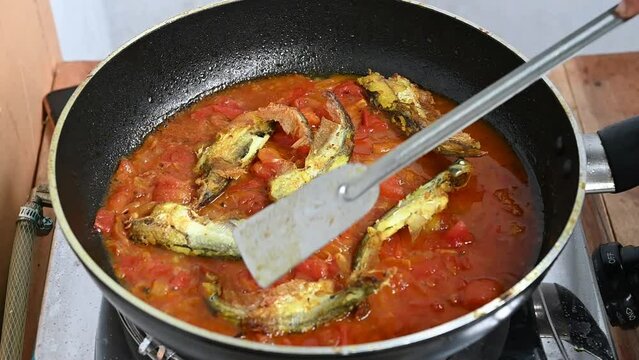 Cooking pabda fish in tomato, onion, oil. Slow motion video