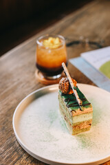 Green tea sliced cake dessert on white plate with summer mocktail in cafe table 