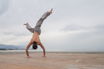 Obraz premium Shirtless caucasian man doing backflip on pebble beach. 
