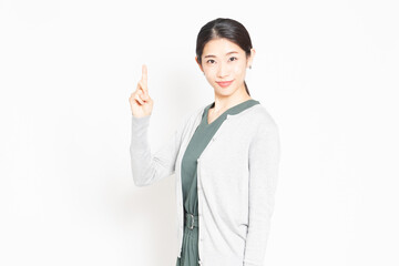 白背景の前に立って、ポイントを示す女性