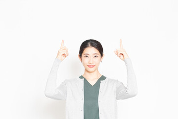 白背景の前に立って、ポイントを示す女性