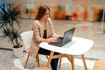 A business woman sits in a cafe working at a computer.