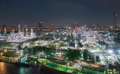 Fototapeta premium Aerial view of petrochemical oil refinery and sea in industrial engineering concept in Bangna district at night, Bangkok City, Thailand. Oil and gas tanks pipelines in industry. Modern metal factory.