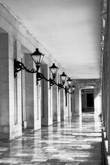 Blick in einen Durchgang mit Säulen und Laternen, schwarz-weiß, vertikal 