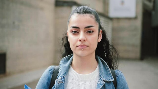Young hispanic serious girl brunette student looking serious at camera. Juvenile teenage lady standing at university campus. Education concept. High quality photo