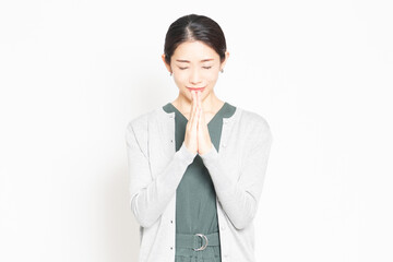 白背景の前で、お願いのポーズをする女性