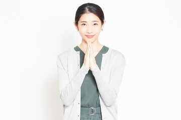 白背景の前で、お願いのポーズをする女性