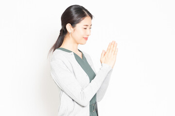 白背景の前で、お願いのポーズをする女性