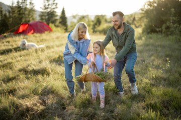 Young caucasian couple with little girl have fun while travel in the mountains. Happy family spending summer vacation at campsite