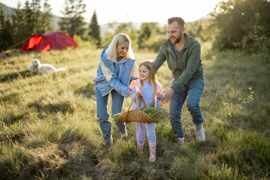 Young caucasian couple with little girl have fun while travel in the mountains. Happy family spending summer vacation at campsite