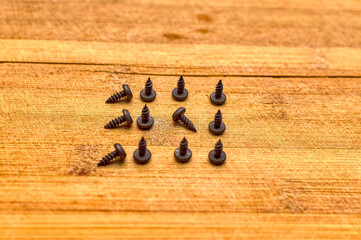 Little black screws on wooden surface.