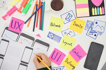 Creative designers designing wireframe sketch layout design mockup on smartphone screen. User...
