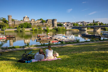 Couple de touriste au pied du château de la ville d'Angers en France. - obrazy, fototapety, plakaty