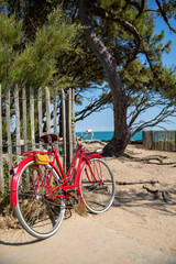 Fototapeta premium Vieux vélo rouge en bord de mer sur le littoral en France.
