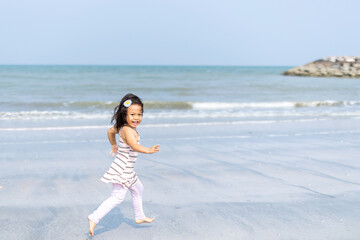 A girl having fun running on the beach by the sea in the daytime, the children's vacation in the summer.