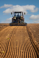 Fototapeta premium Agriculteur au volant de son tracteur labourant son champ au printemps.