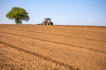 Tracteur en train de labourer la terre de son champ au printemps.