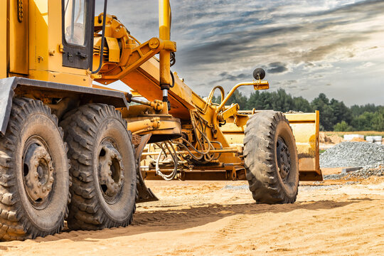 Road grader at the construction site. Powerful construction machine for ground leveling and excavation. Close-up. Professional construction equipment.