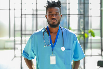 Portrait of male doctor wearing medical coat standing in hospital corridor.