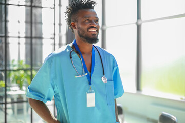 Portrait of male doctor wearing medical coat standing in hospital corridor.