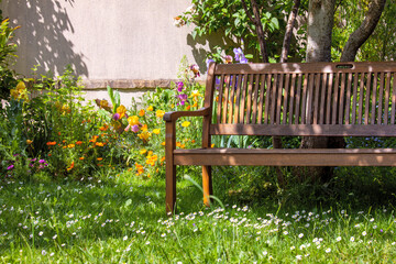 Banc en bois dans un charmant petit jardin fleuri au printemps.