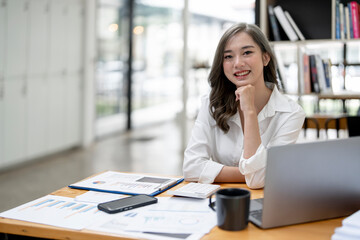 Portrait of smiling lady entrepreneur working on laptop at workplace in modern office.