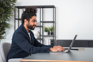 Arab businessman typing on laptop, home office interior