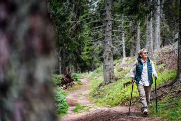 Active happy mature senior woman walking in beautiful autumn forest
