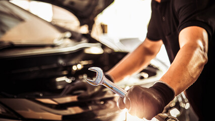 Close-up hand auto mechanic holding the wrench to repairing car engine problem. Concepts of check and fix car and maintenance servicing.