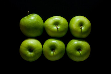 Six green apples isolated on a black background, top view.