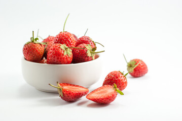 Strawberries are placed in a white ceramic cup. and put on a white background.