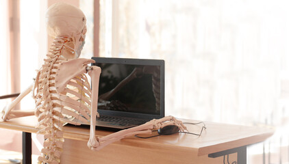 Skeleton in a medical mask using a computer in the office
