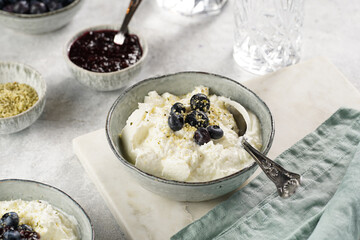 Two grey bowls with plain white icelandic diary breakfast skyr with jam, fresh blueberries, hemp...