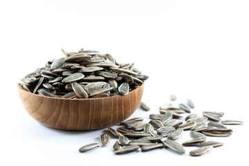 Sunflower seeds in a wooden bowl placed on a white floor.