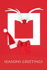 Christmas seasons greetings abstract, santa hat, reindeer antlers, bow on red background and white frame border. Traditional symbols for the holiday season.